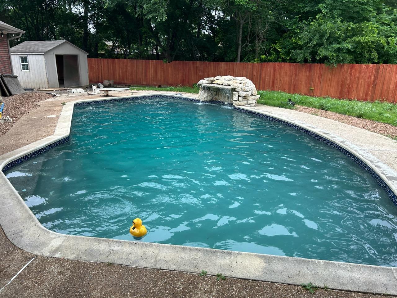 Clean backyard pool with water feature