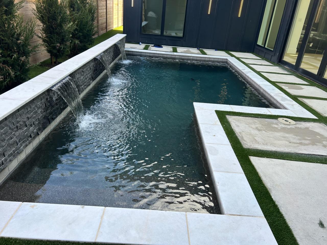 Clean backyard pool with a modern water feature after service