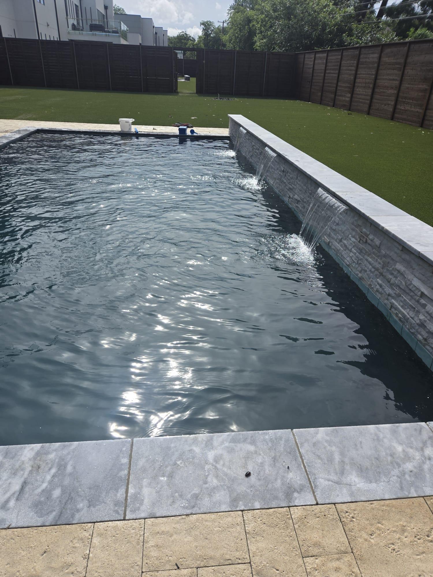 Backyard pool with clear water and water feature after service